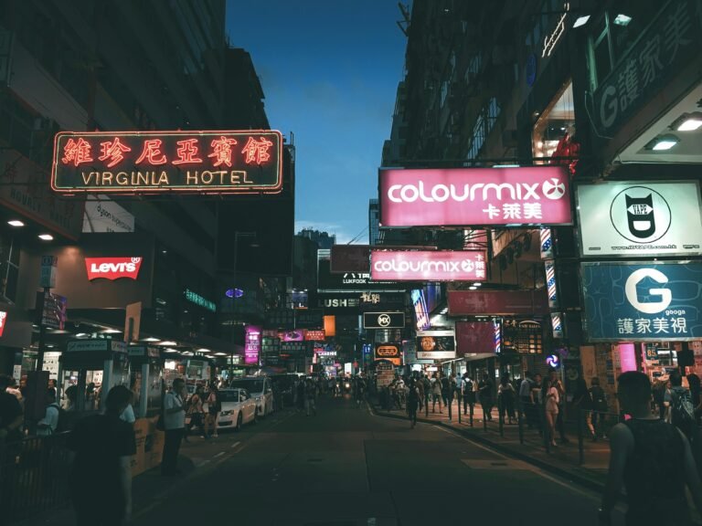 crowd walking on pathway surrounded by buildings during night time